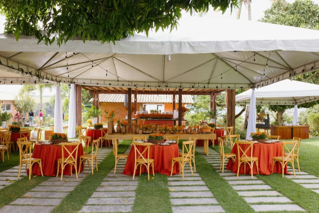 Covered outdoor pavilion set with colourful linens and wooden chairs on a paved garden terrace
