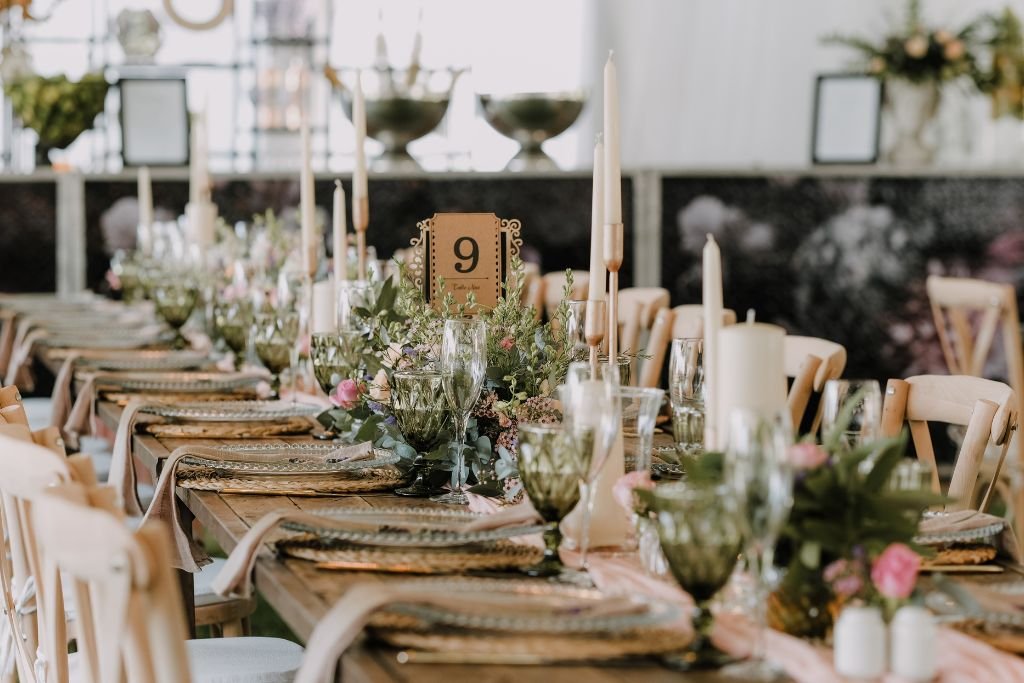 Long wedding table set with a greenery runner, taper candles, glassware and a numbered table card
